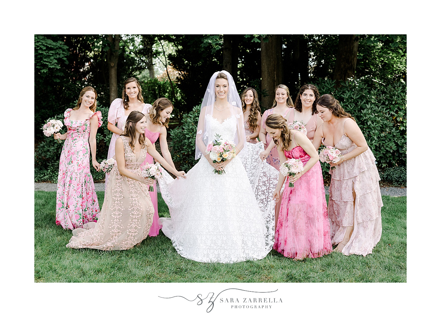 bride stands with bridesmaids in mismatch pink gowns on lawn at the Chanler