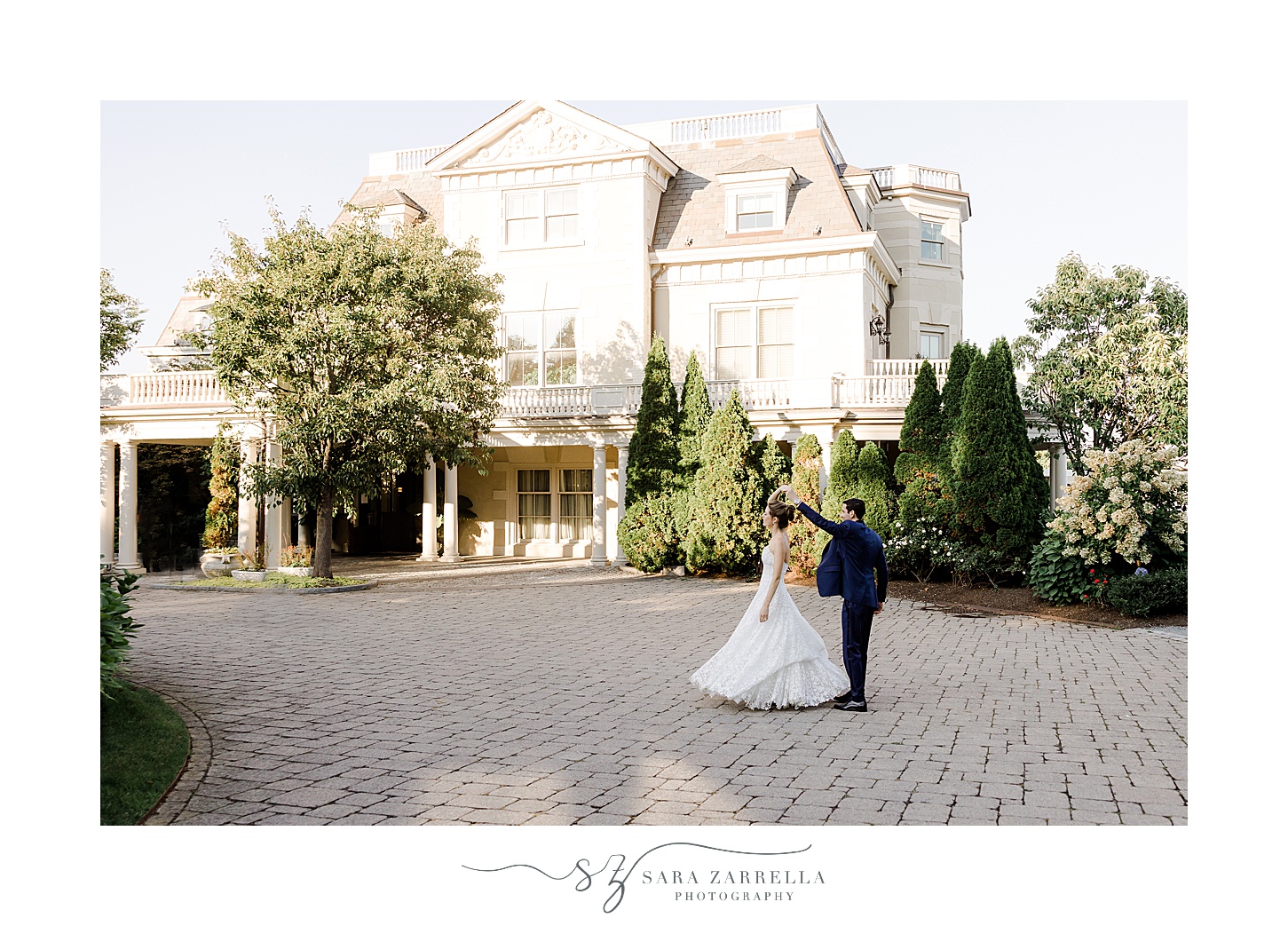 bride and groom kiss on driveway with the Chanler behind them 
