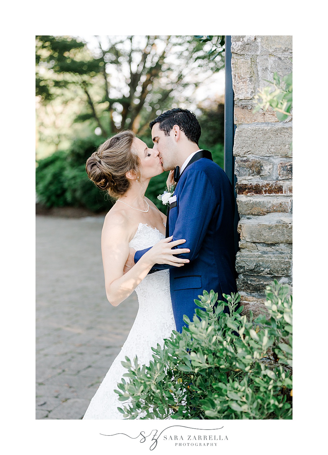 bride and groom kiss leaning against stone pillar at the Chanler