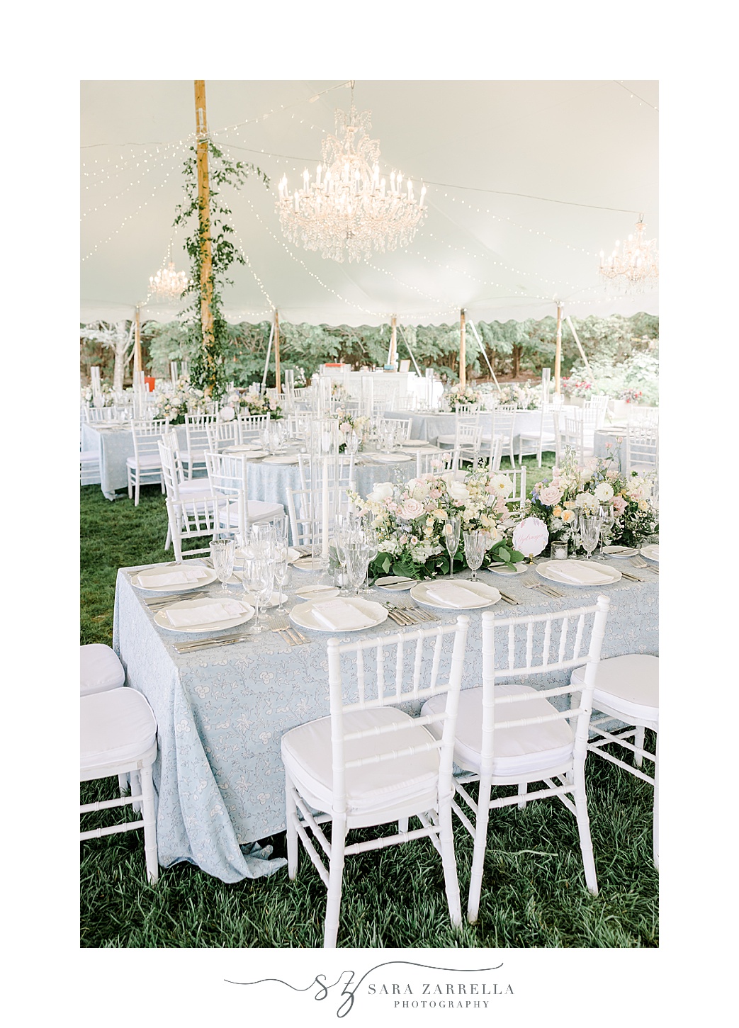 family style seating under tent with greenery and ivory flowers at the Chanler