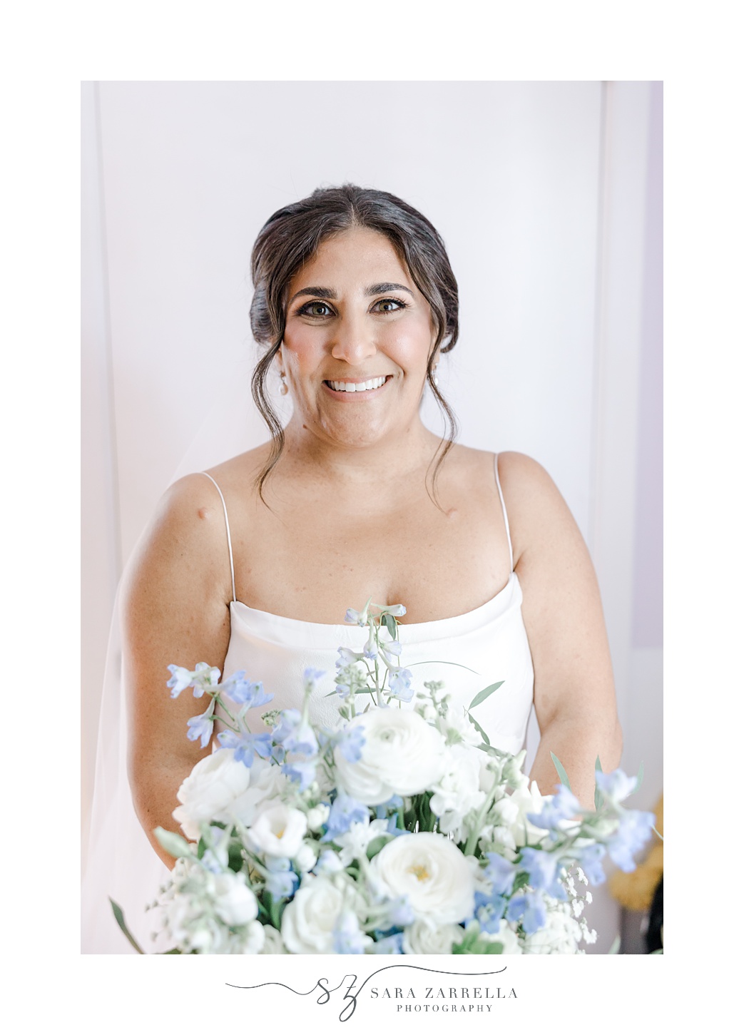 bride holds bouquet of blue and white flowers for summer wedding in Rhode Island 