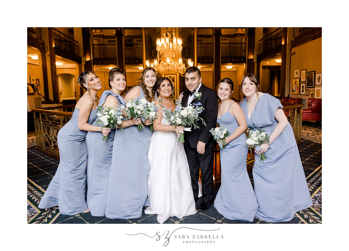 bride poses with bridesmaids in light blue gowns in lobby of the Graduate Providence
