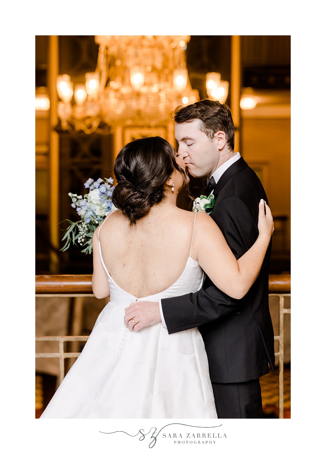 bride and groom kiss near staircase and chandelier at the Graduate Providence