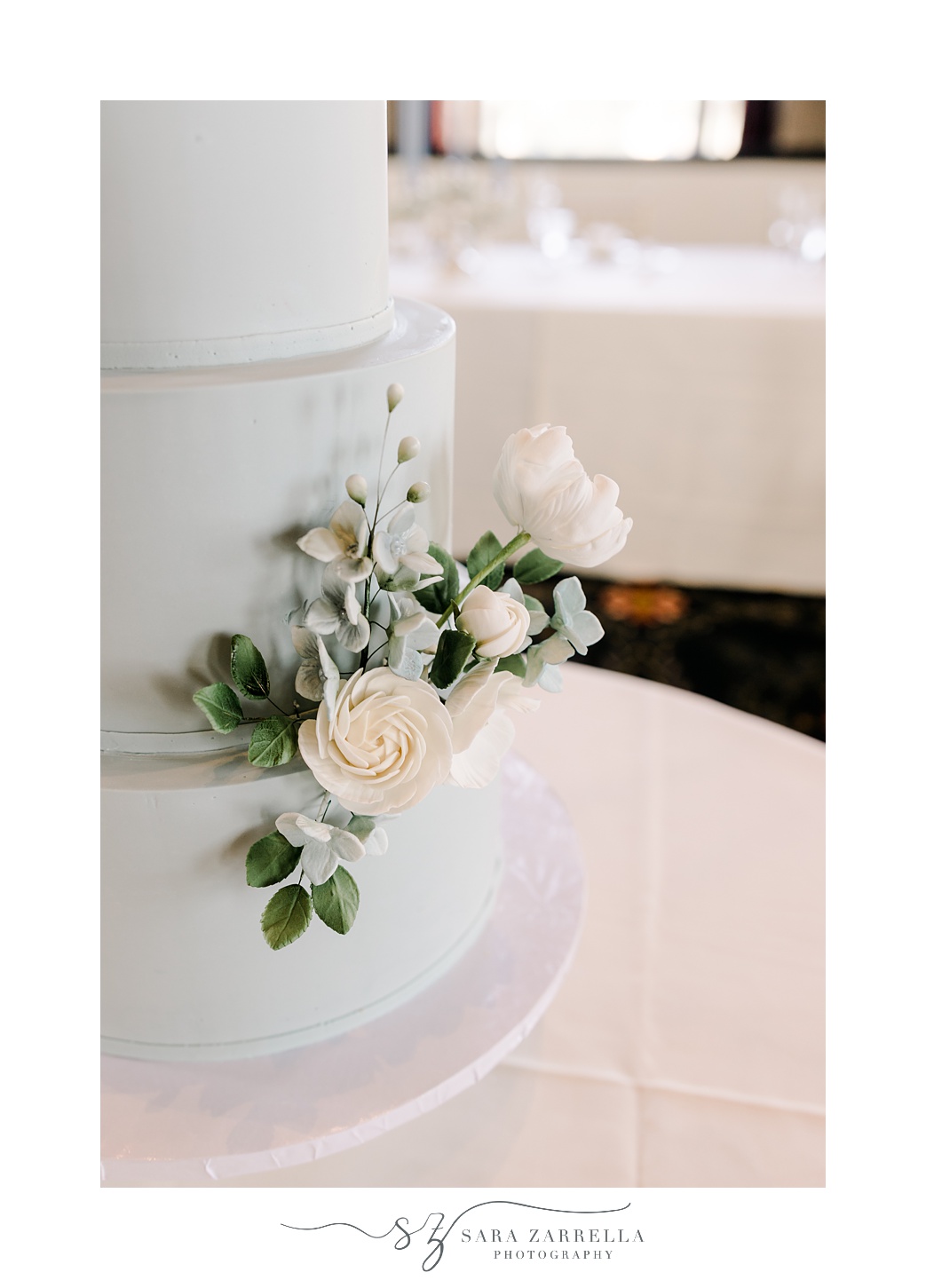 tiered wedding cake with blue icing and ivory flowers 
