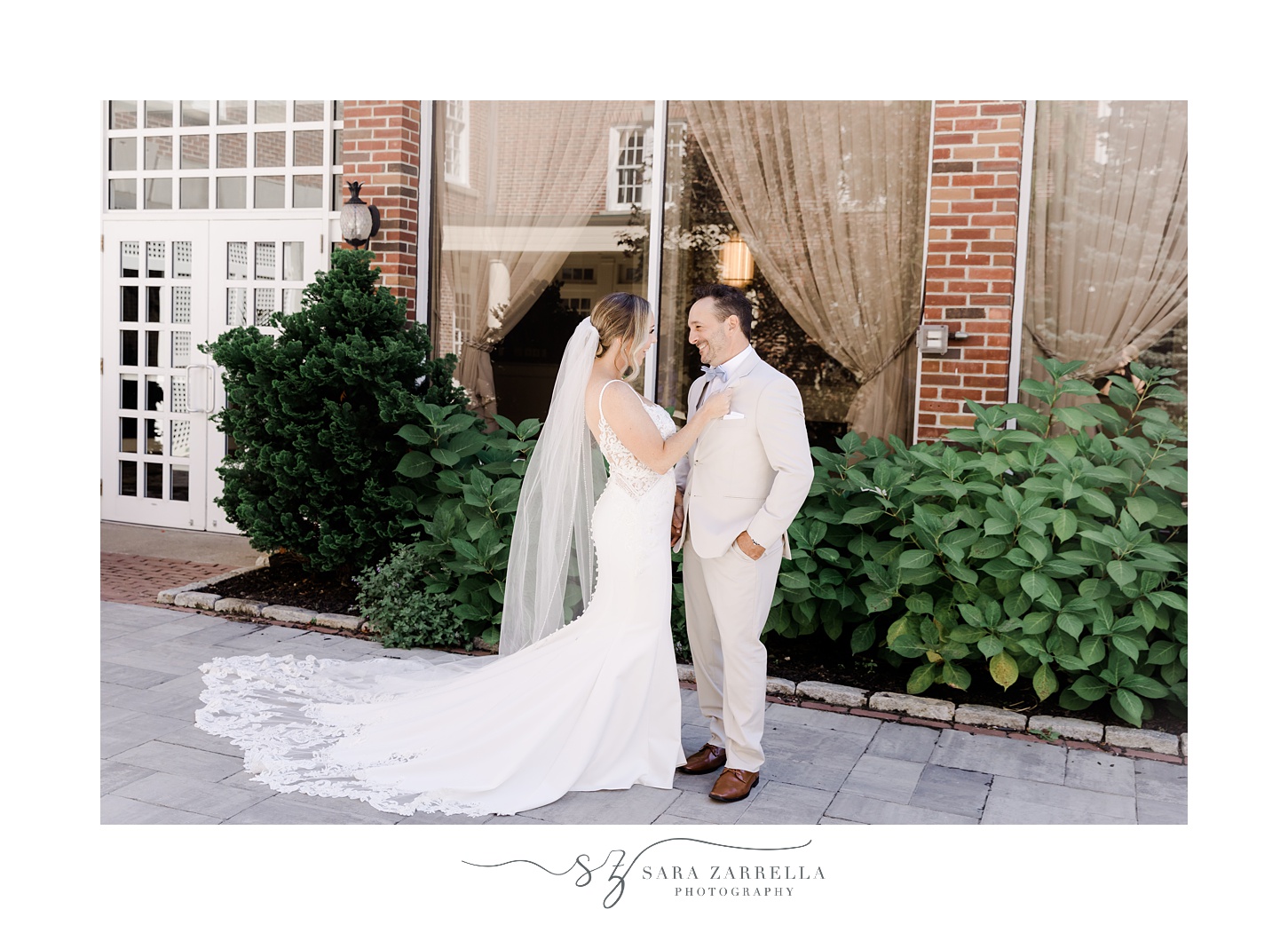 bride and groom hug in front of window and brick wall at Regatta Place