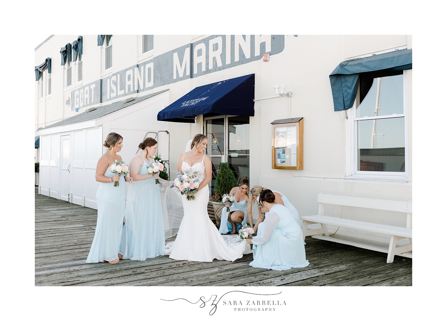 bridesmaids in blue gowns help bride with skirt of wedding gown on dock at Regatta Place