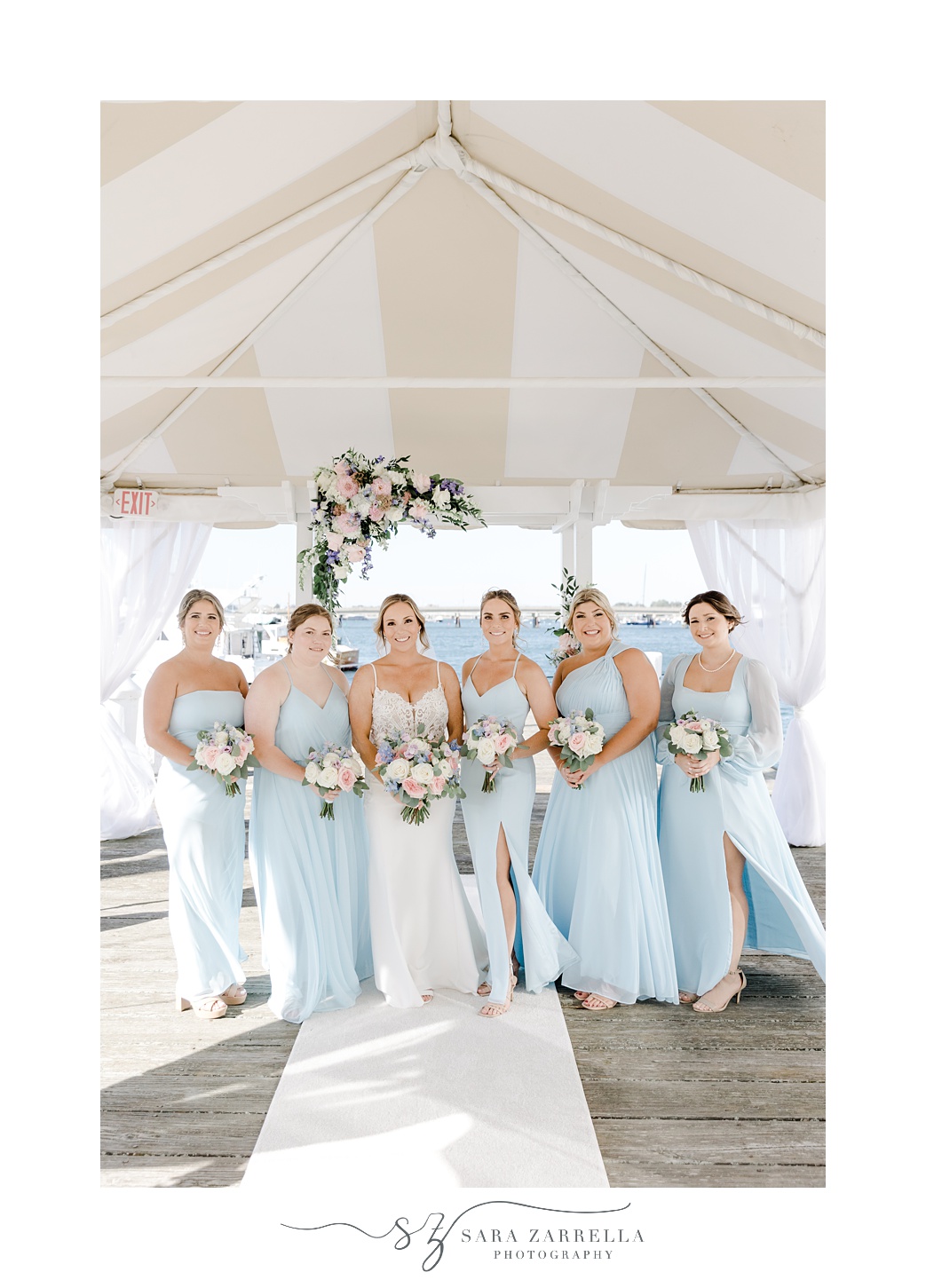 bride stands with bridesmaids on dock at Regatta Place