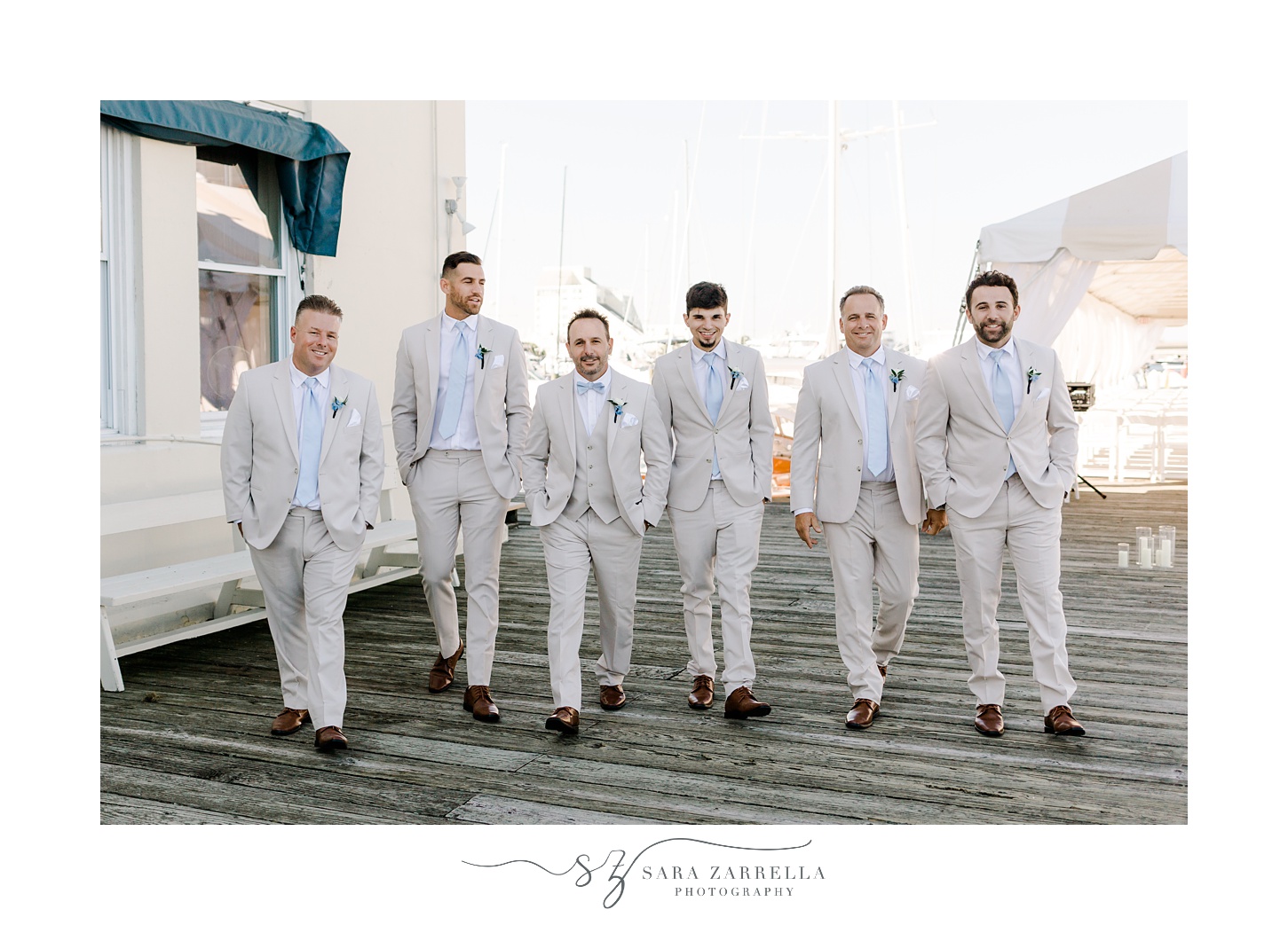 groom walks with groomsmen in tan suits on dock at Regatta Place