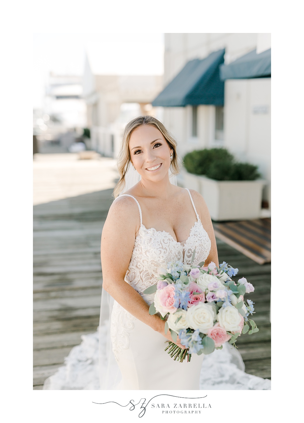 bride holds bouquet of pink and white flowers on docks outside Regatta Place