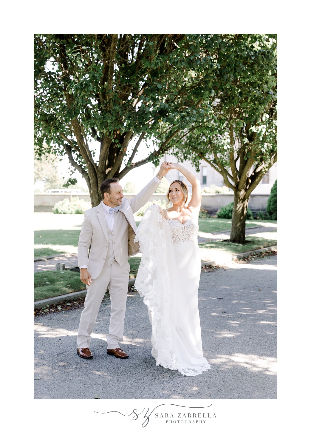 groom twirls bride under his arm outside Newport mansion
