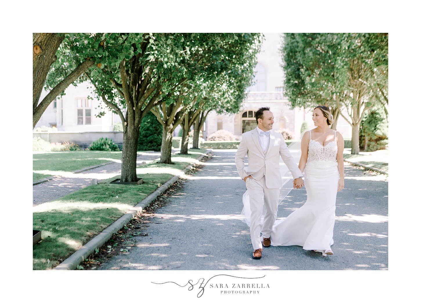 newlyweds walk down aisle between rows of trees outside Newport mansion