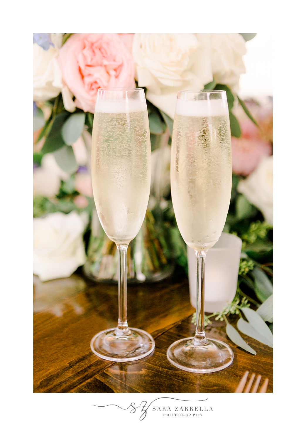 two glasses of champagne on table with pink and white flowers 