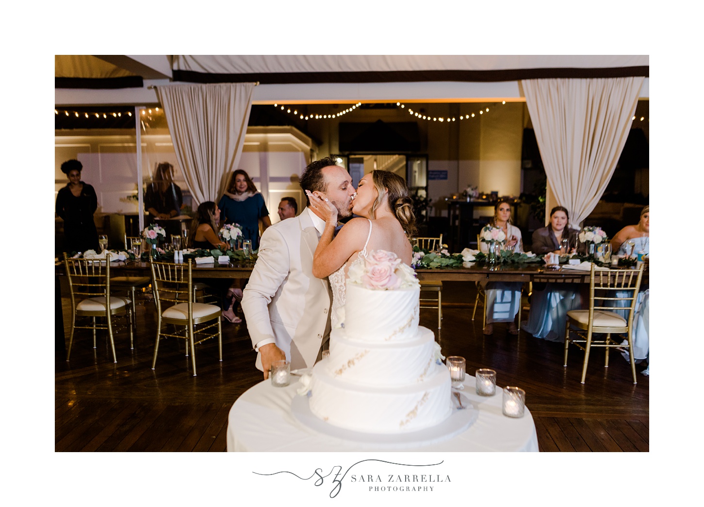 newlyweds kiss near wedding cake during Newport RI wedding reception