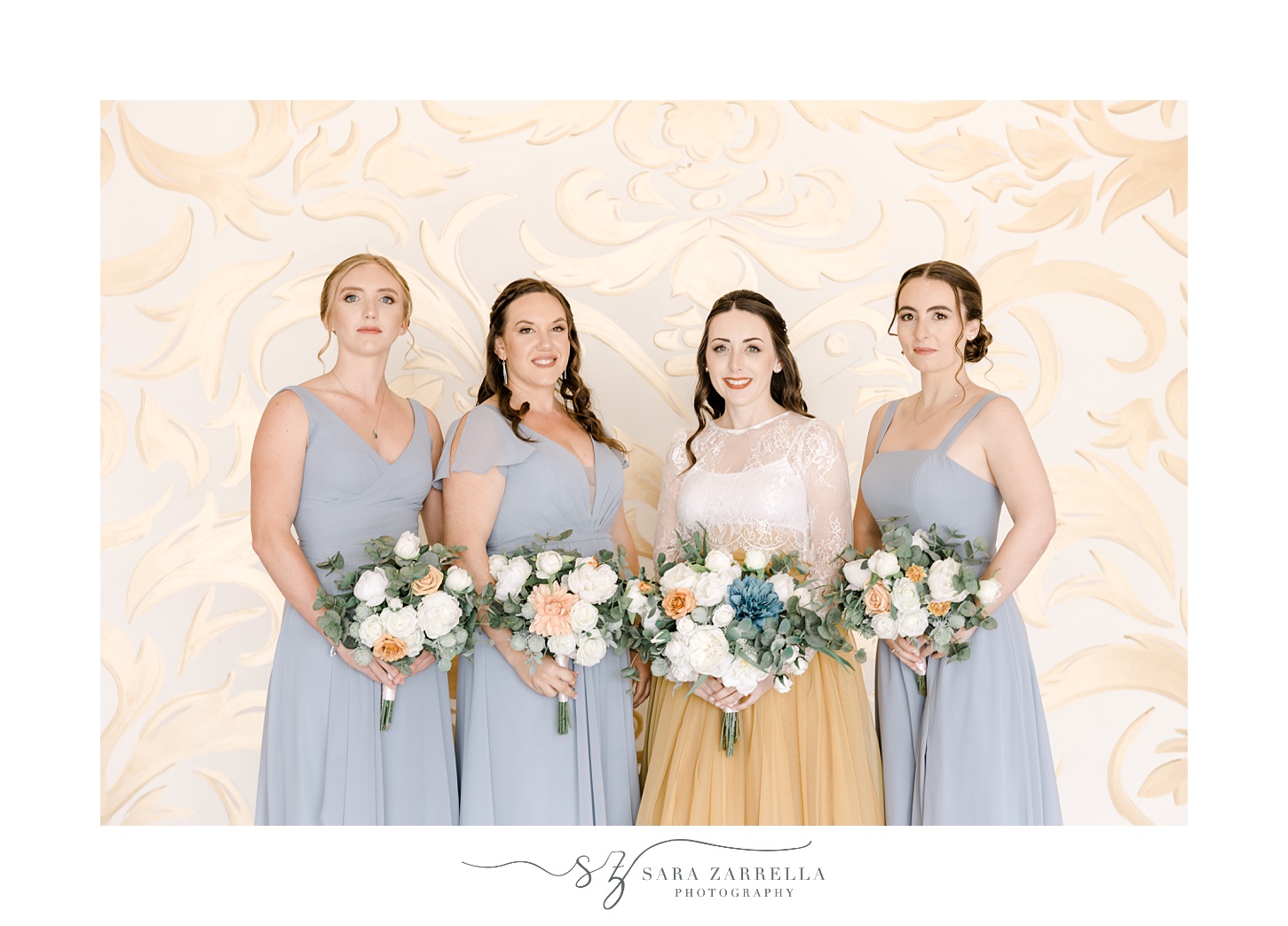 bride and bridesmaids in light blue gowns smile in front of gold wall at the Atlantic Wyndham Resort