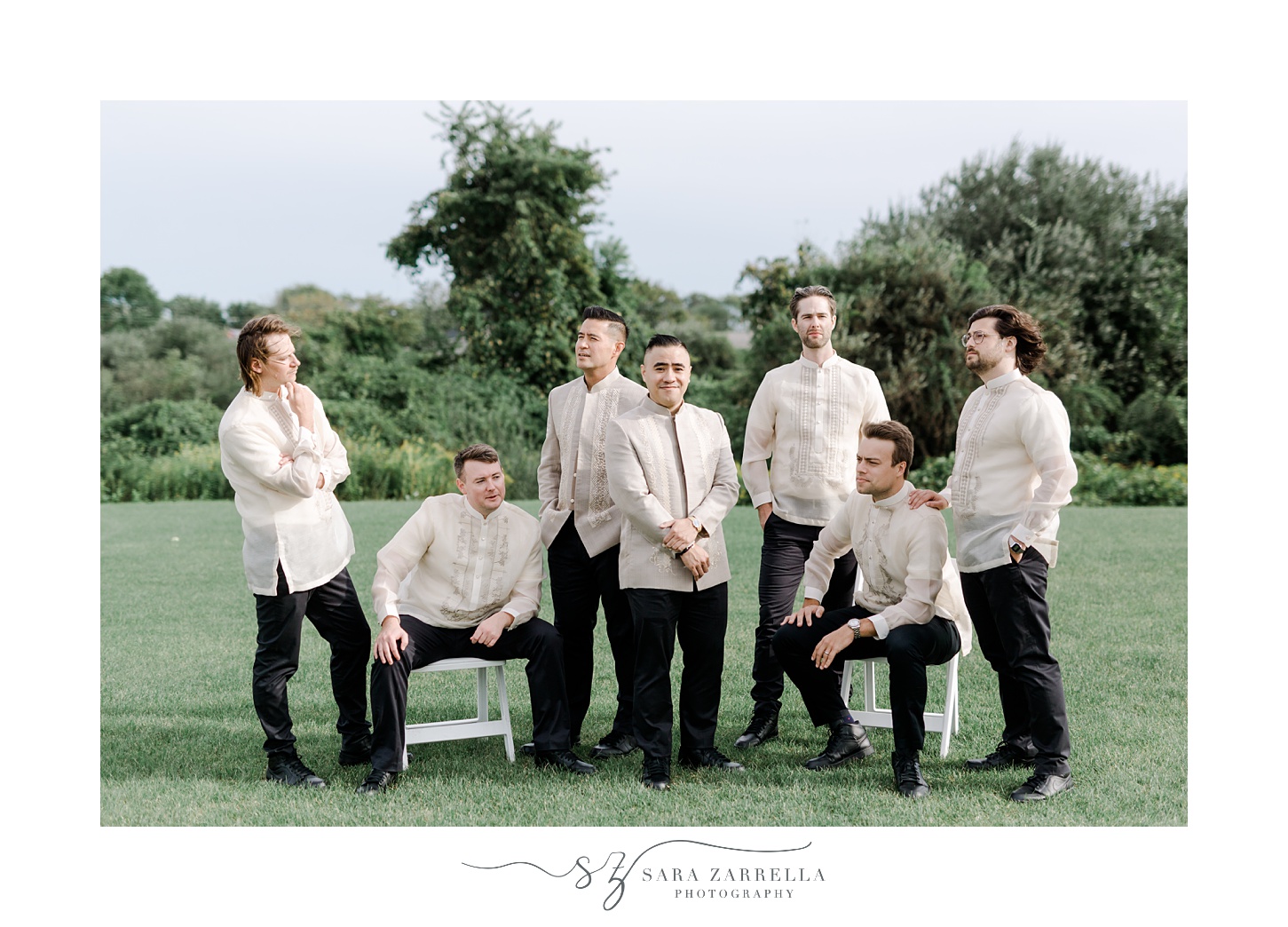 groom and groomsmen stand and sit on lawn at the Atlantic Wyndham Resort