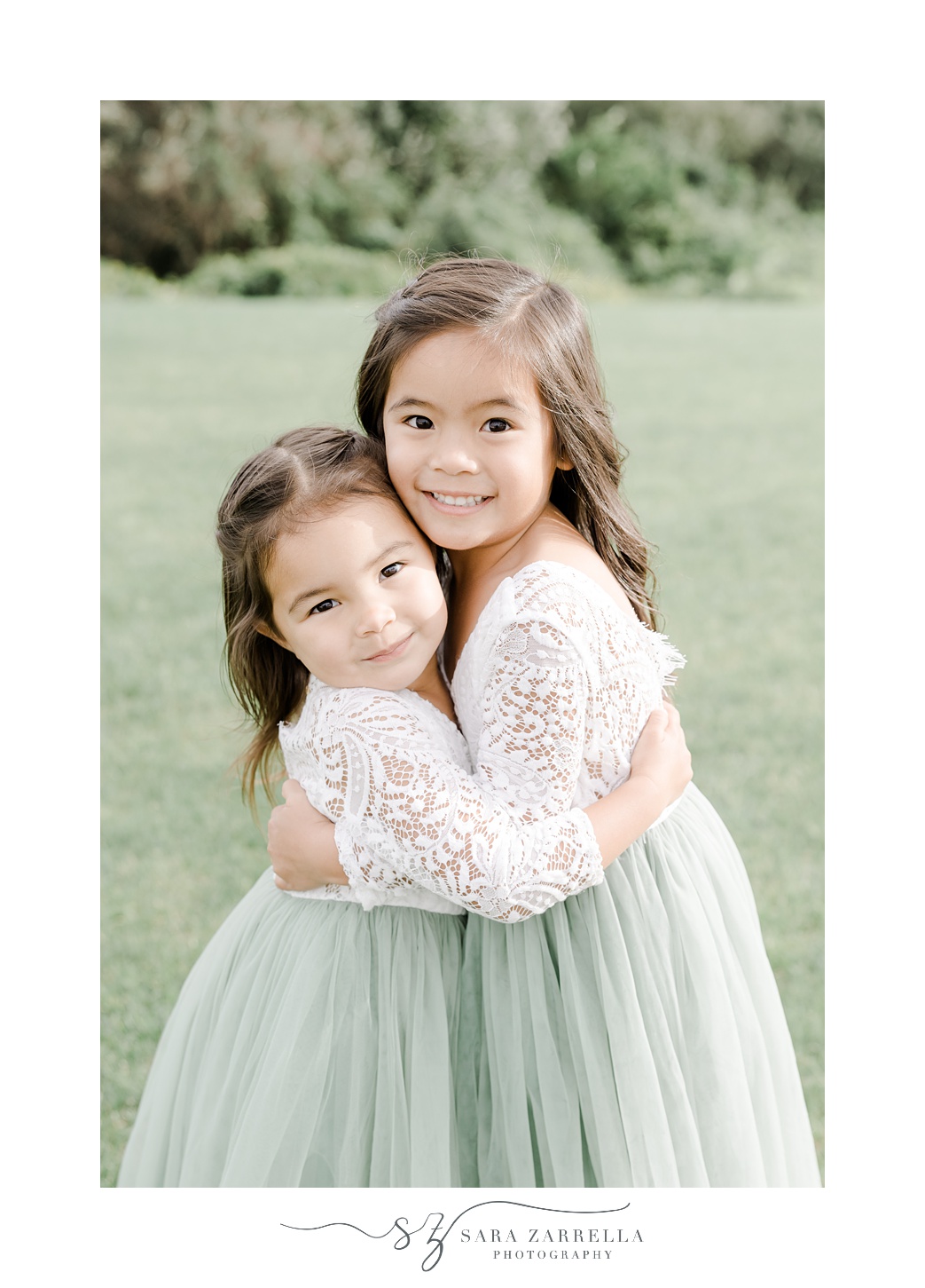 flower girls in lace tops and green skirts hug on lawn of the Atlantic Wyndham Resort
