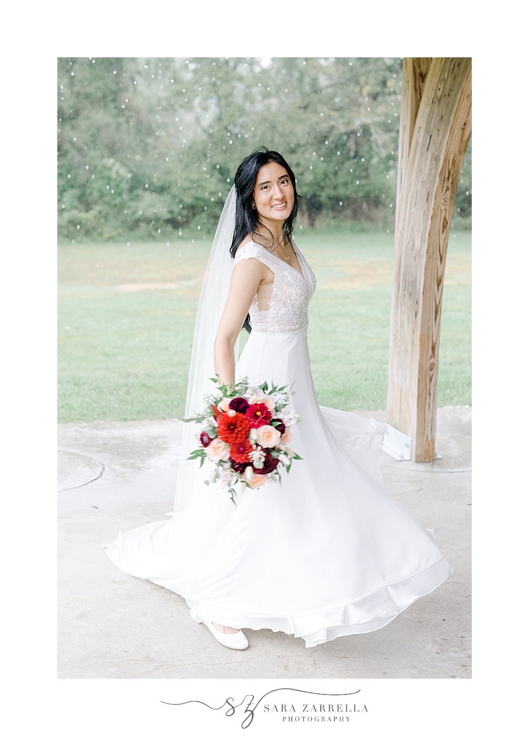 bride twirls in wedding dress with red and pink bouquet at Colt State Park