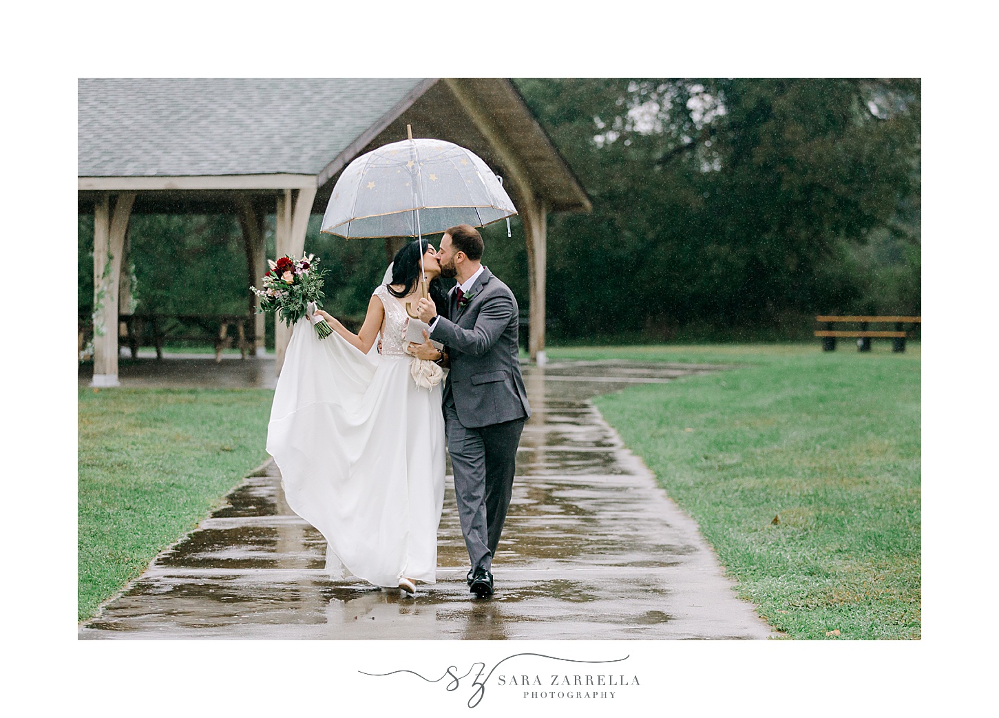 bride and groom kiss walking under umbrella outside Colt State Park