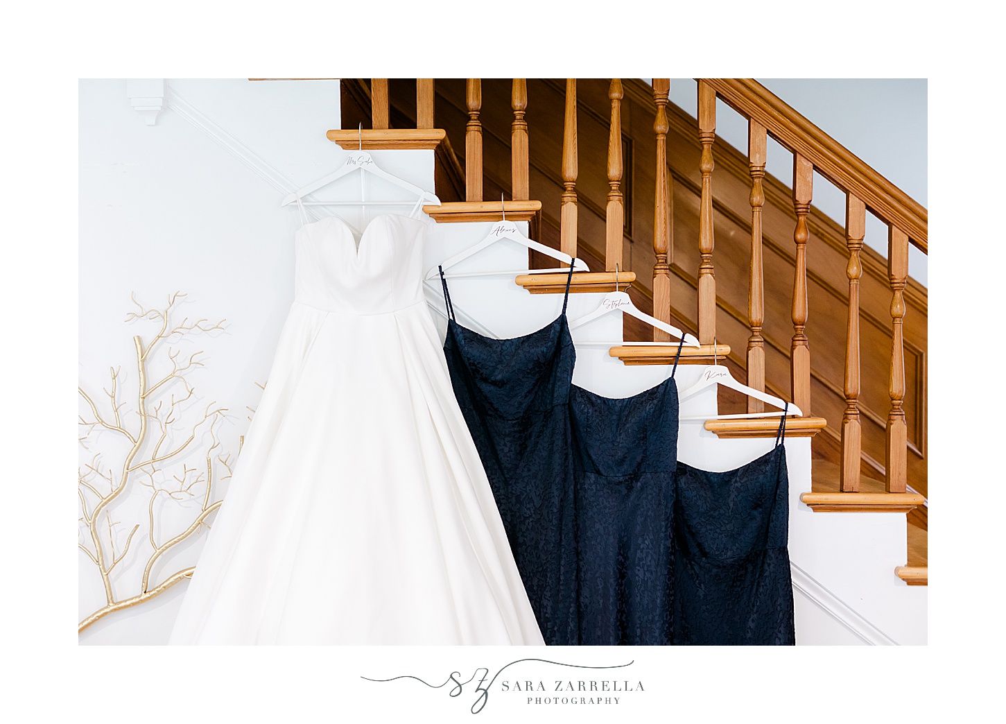 wedding dress hangs on staircase with navy blue bridesmaid dresses 