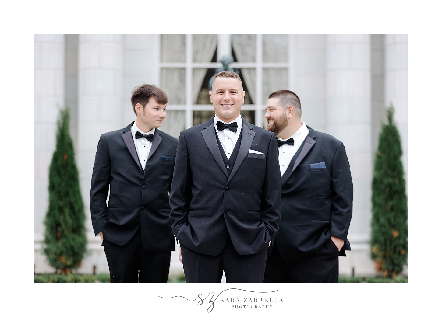 groom and groomsmen laugh standing in black suits 