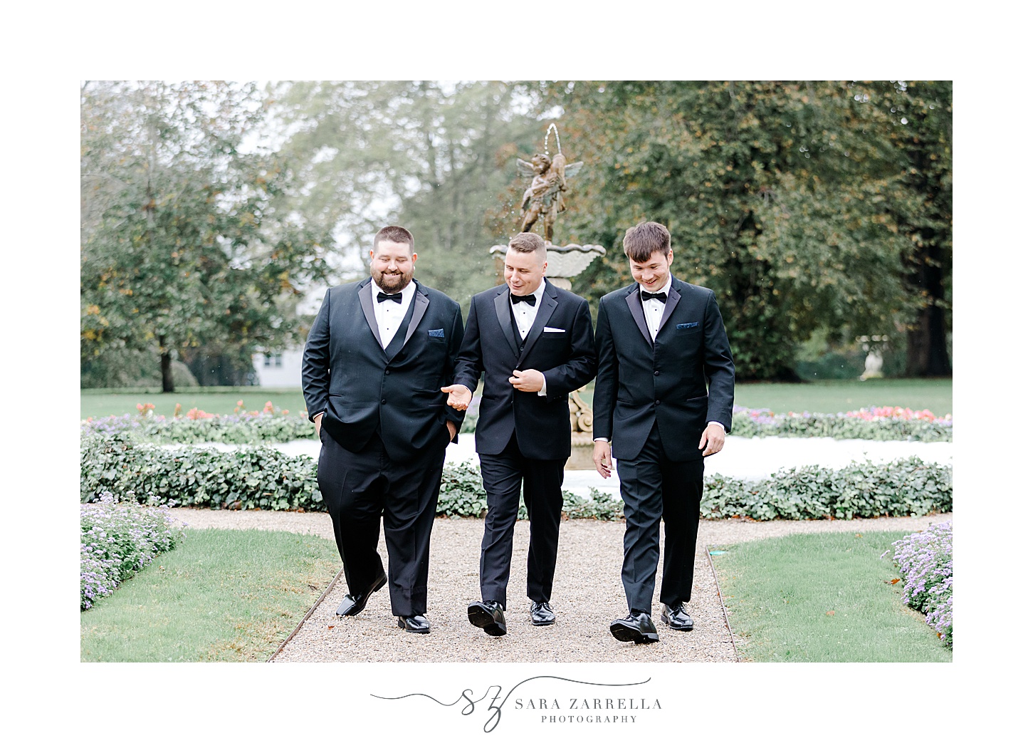 groom walks with groomsmen along pathway outside Rosecliff Mansion