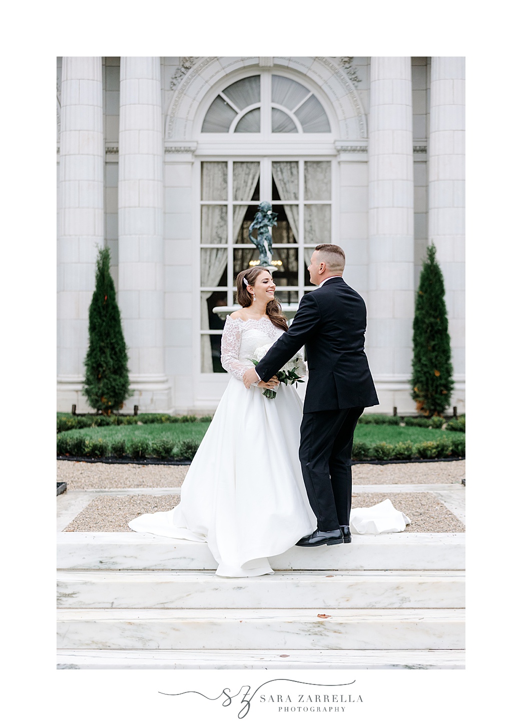 bride and groom twirl outside large window at Rosecliff Mansion