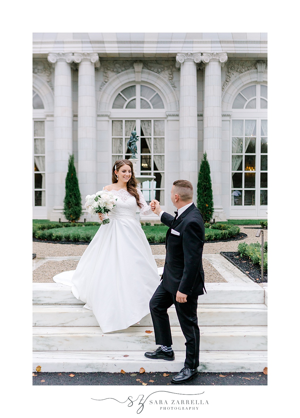 groom walks bride down steps outside Rosecliff Mansion