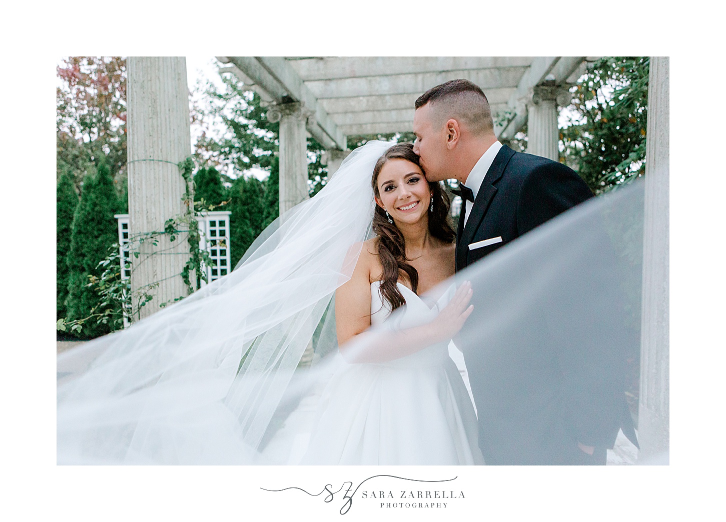 bride and groom kiss with bride's veil under arbor at Rosecliff Mansion