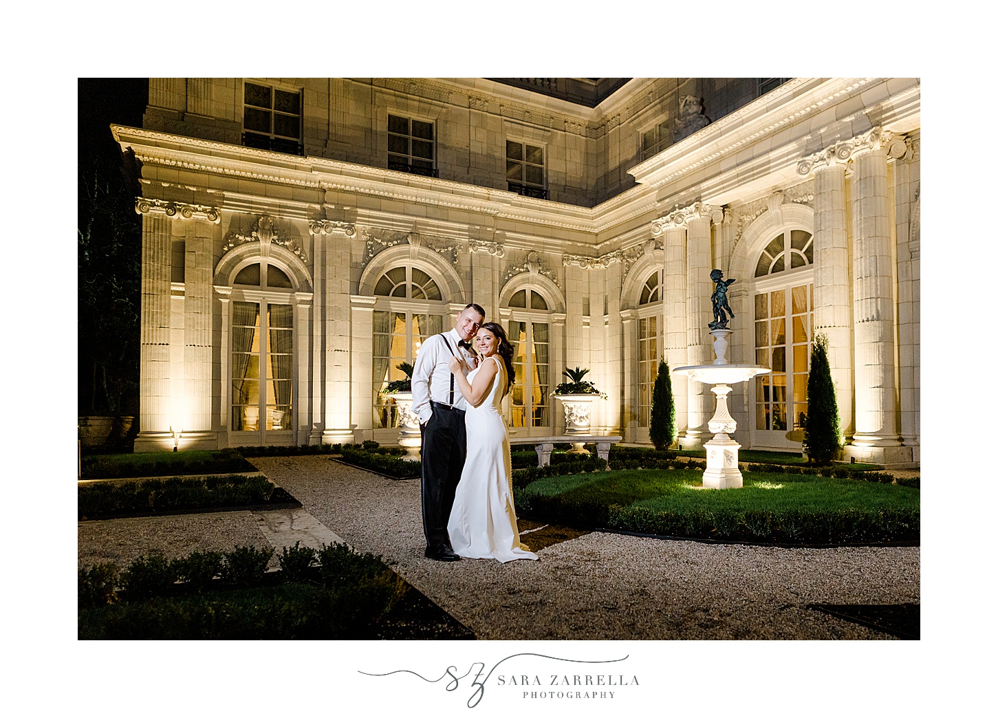 newlyweds hug during nighttime portraits outside Rosecliff Mansion