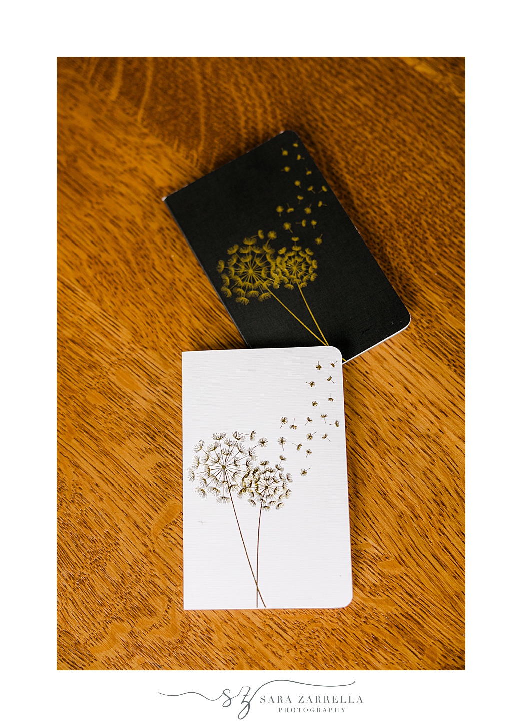 black, white, and gold vow booklets with dandelions on cover