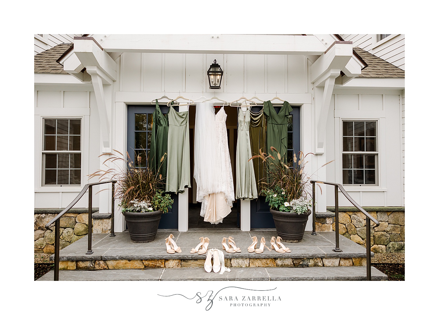 wedding dress hangs with green bridesmaid gowns on front of private home