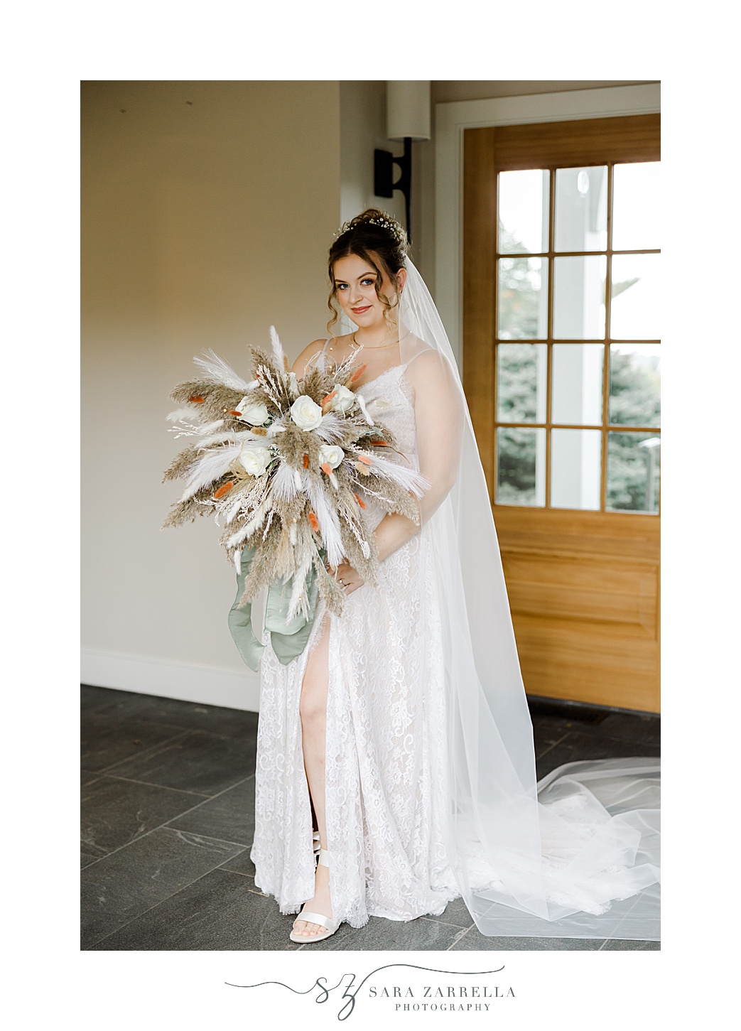 bride holds bouquet of ivory roses with feathers