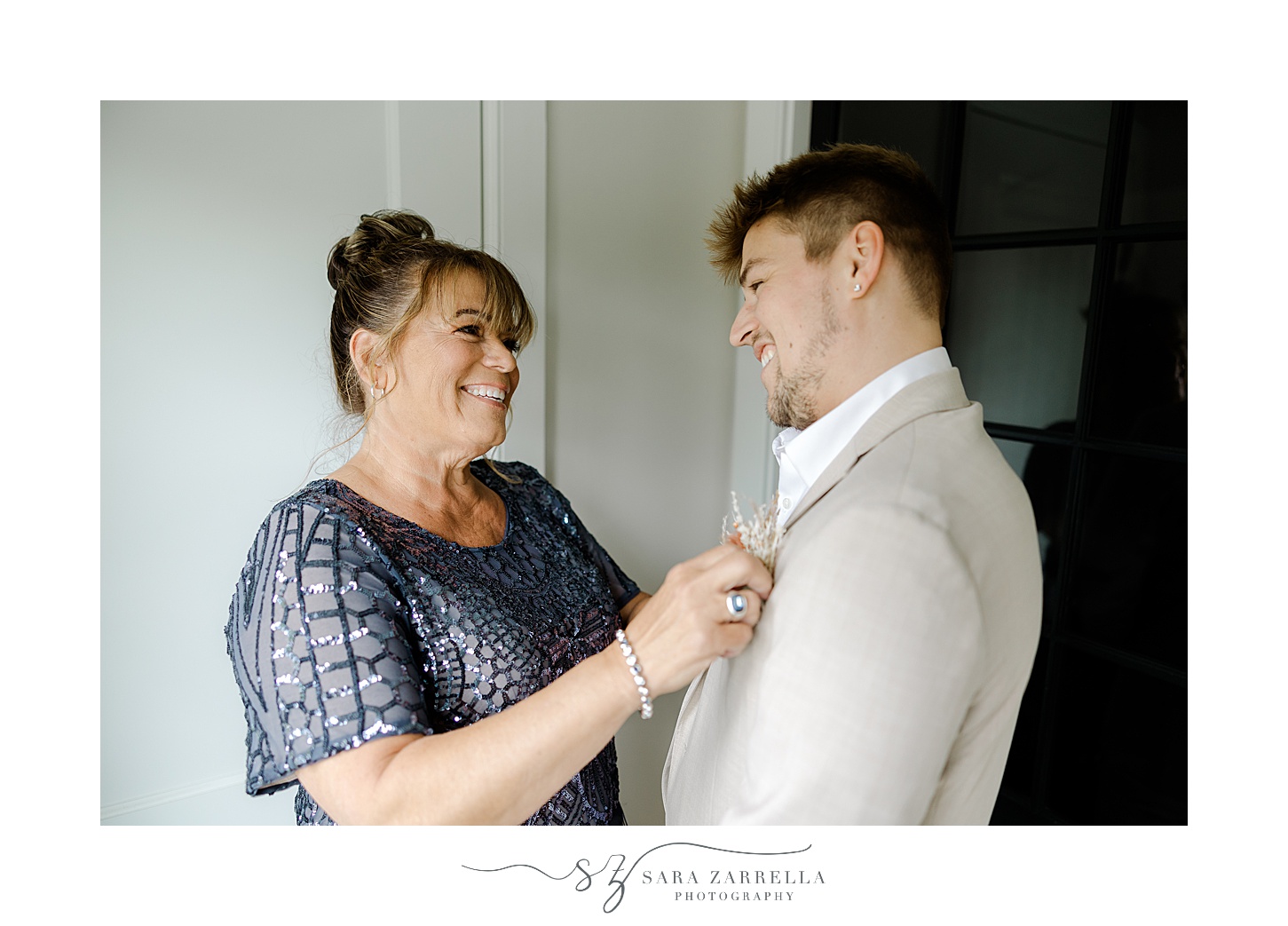 mother helps groom with boutonnière on morning of Rhode Island wedding