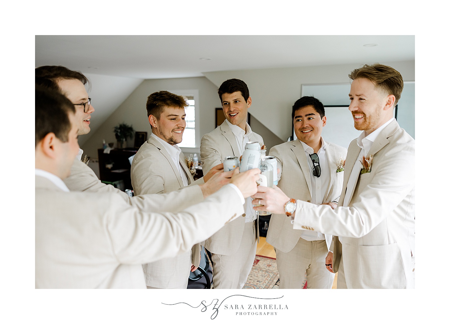 groom and groomsmen in tan linen suits toast drinks