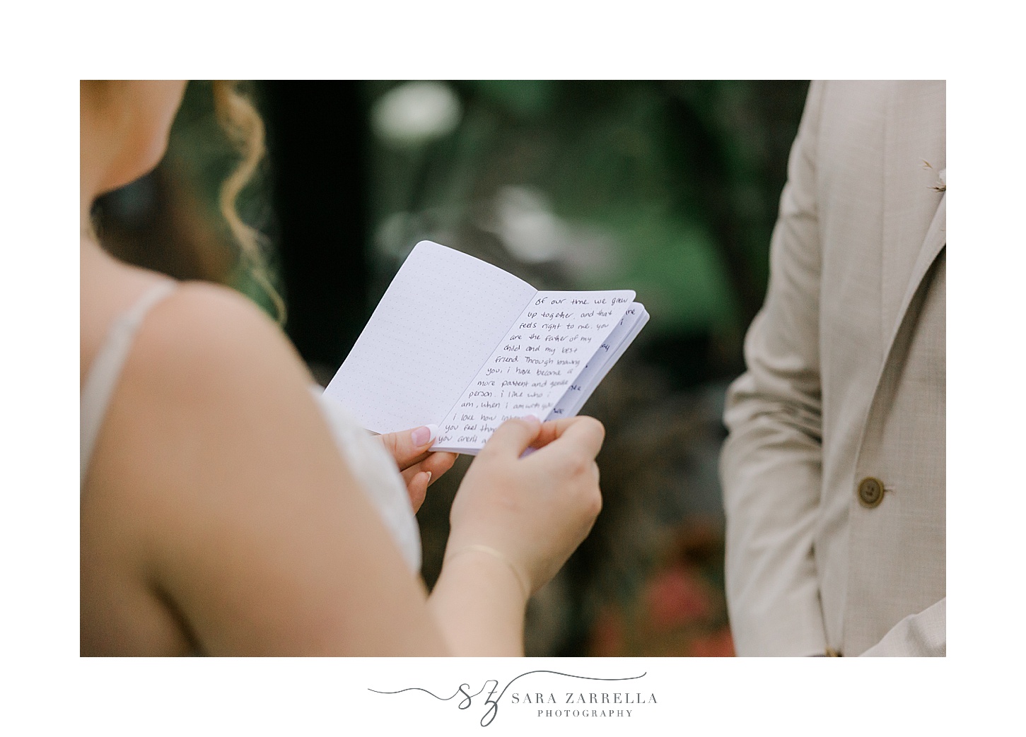 bride reads from vow booklet to man in tan suit