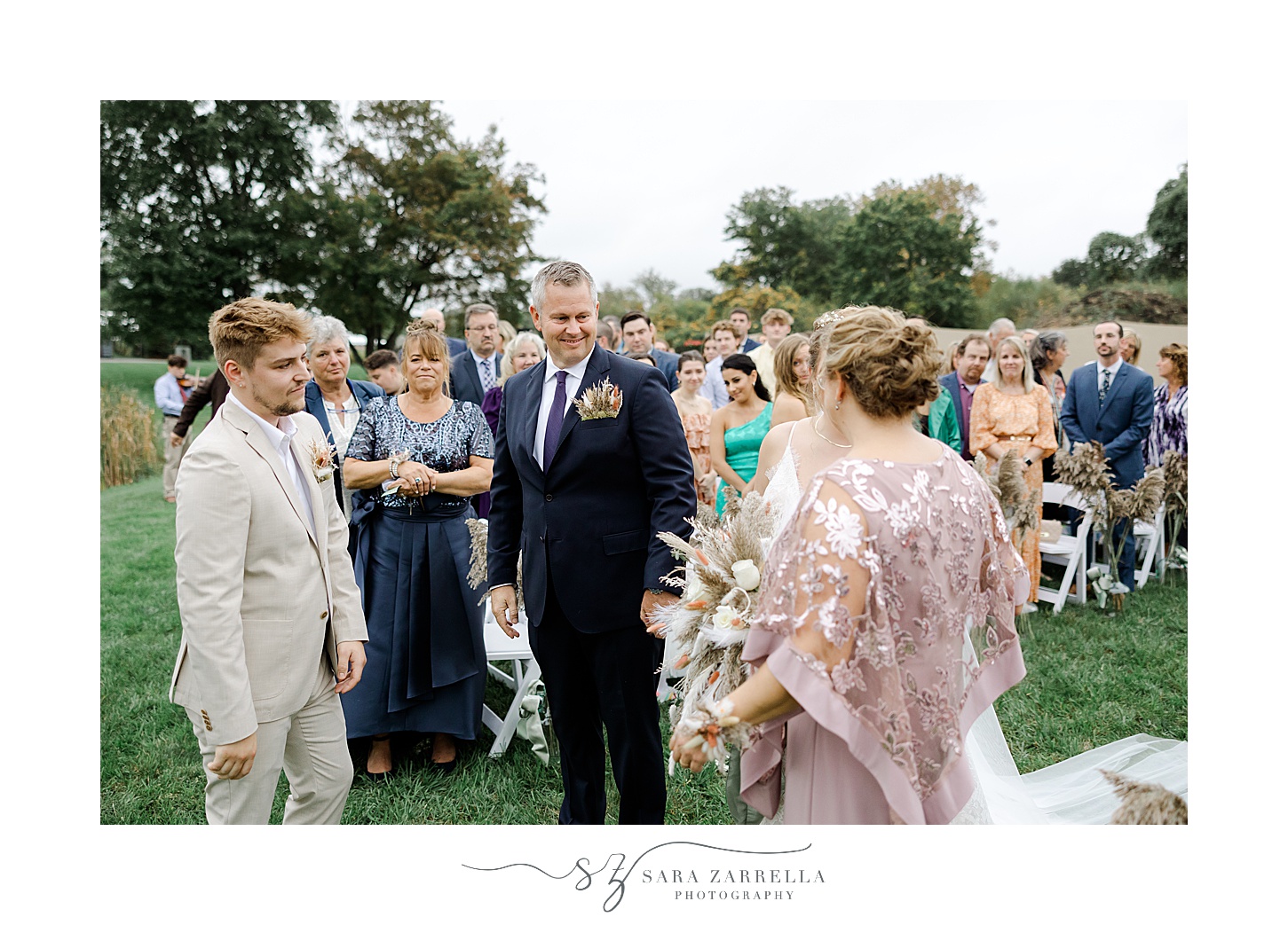 bride and parents stand with groom during ceremony on lawn of private Saunderstown RI home