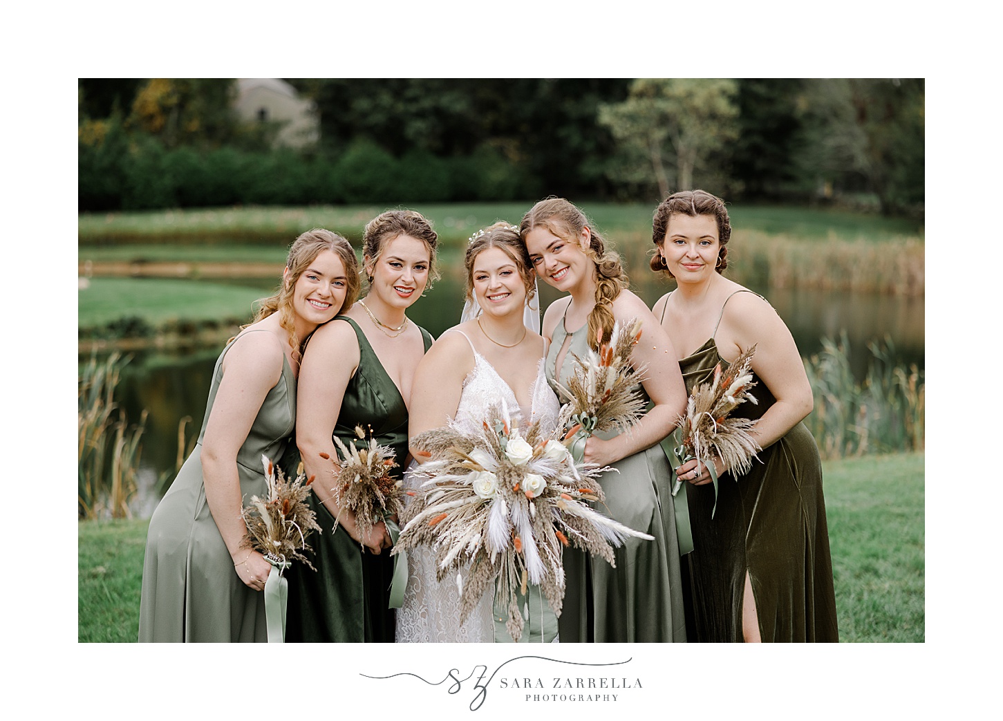 bride stands with bridesmaids in mismatched green gowns on lawn in Rhode Island