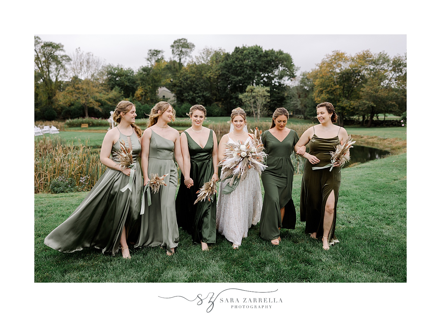 bride stands with bridesmaids in mismatched green gowns on lawn in Rhode Island