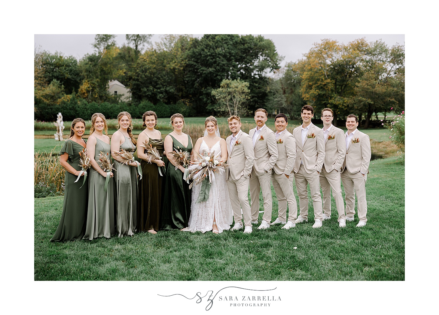 newlyweds stand with wedding party in tan and green attire