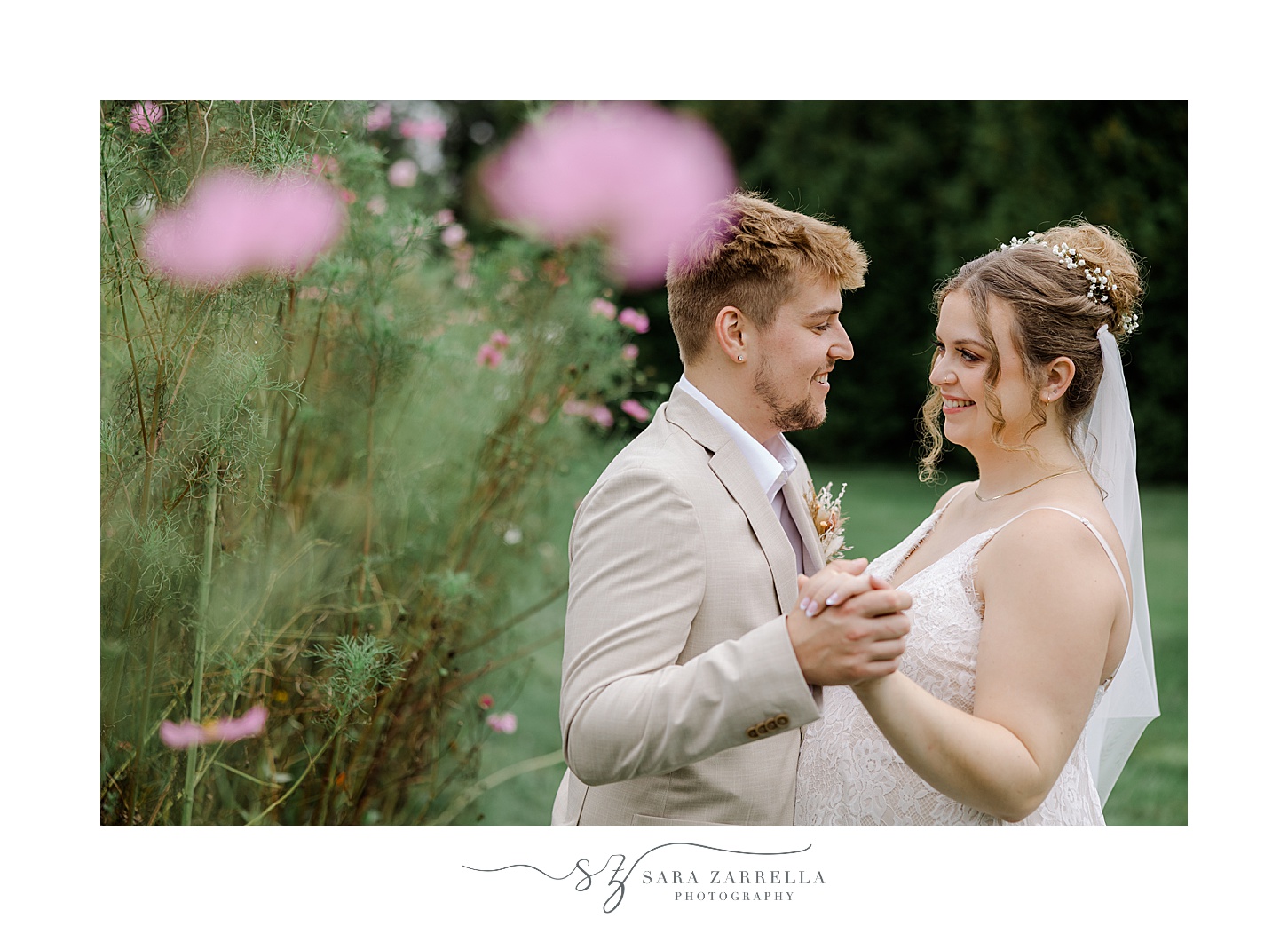 bride and groom hug near pink wildflowers on Rhode Island property