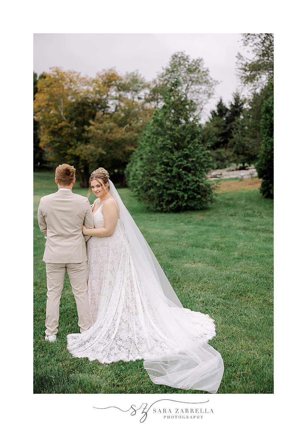 bride holds groom's arm looking over his shoulder in Rhode Island