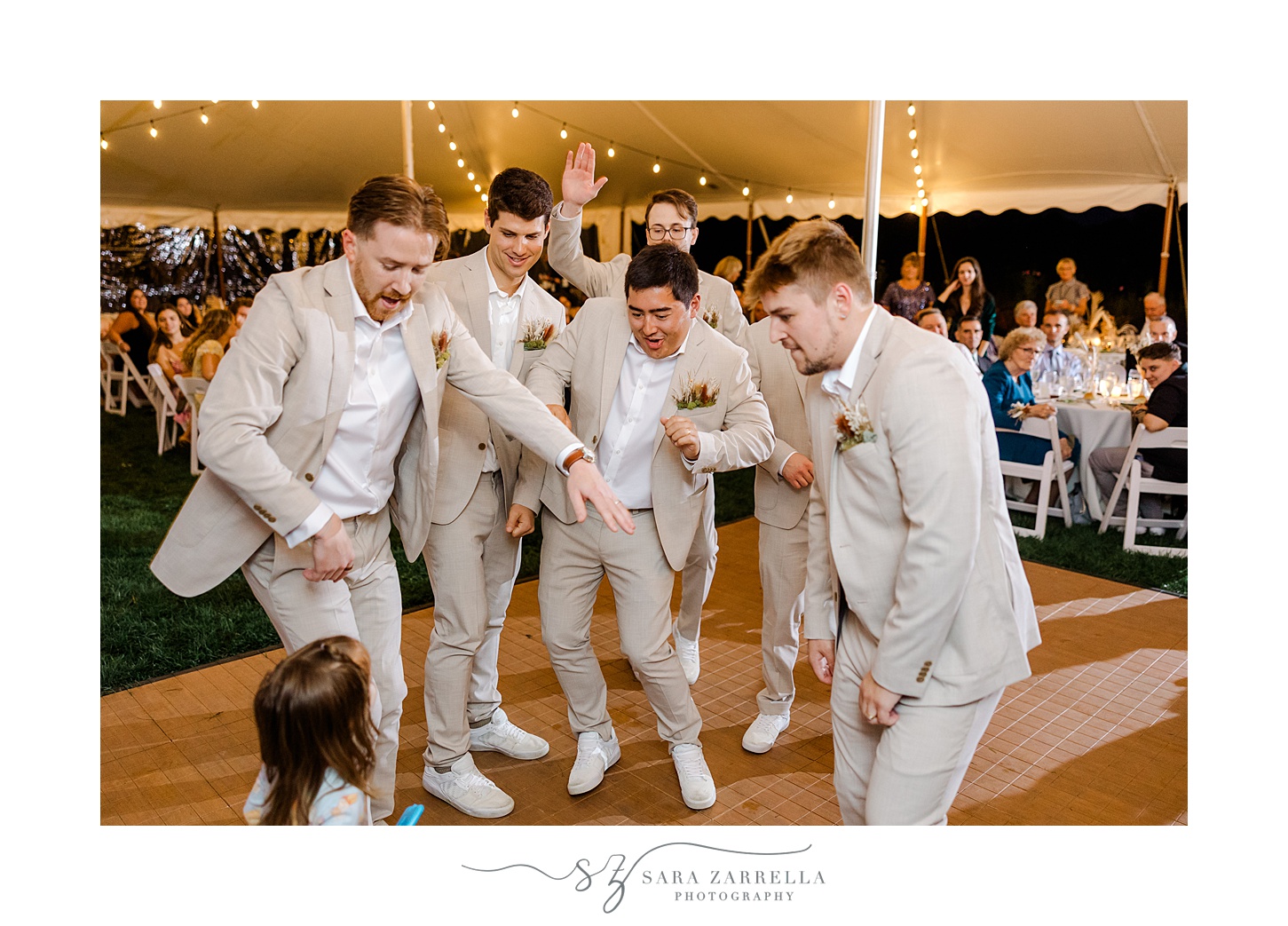 groomsmen dance with groom during wedding reception under tent