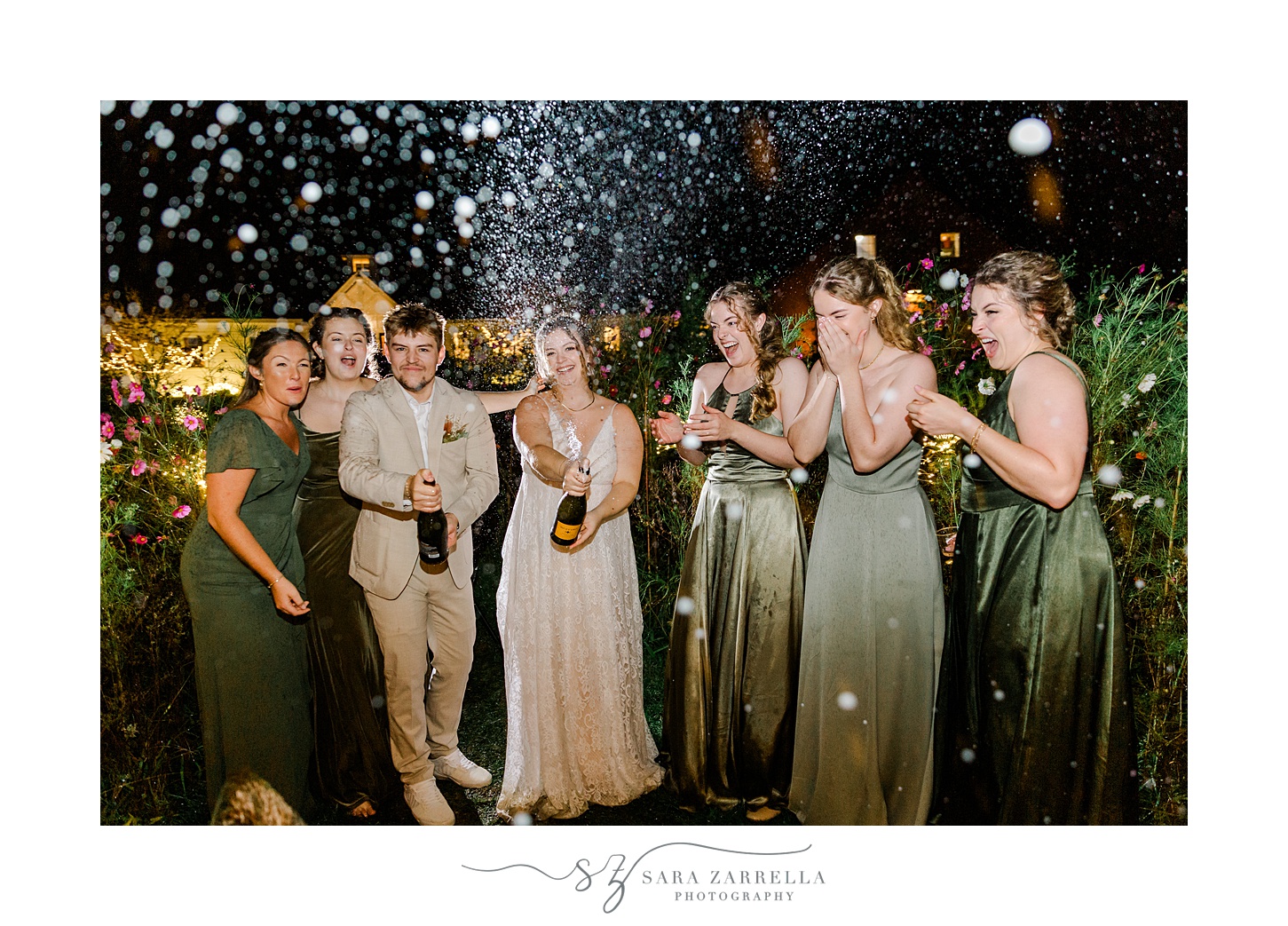 bride and groom pop champagne at night with bridal party