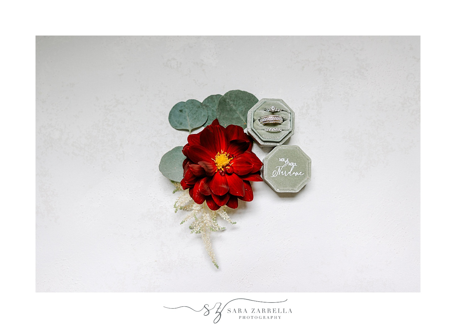 red flower rests between green ring box for RI wedding day