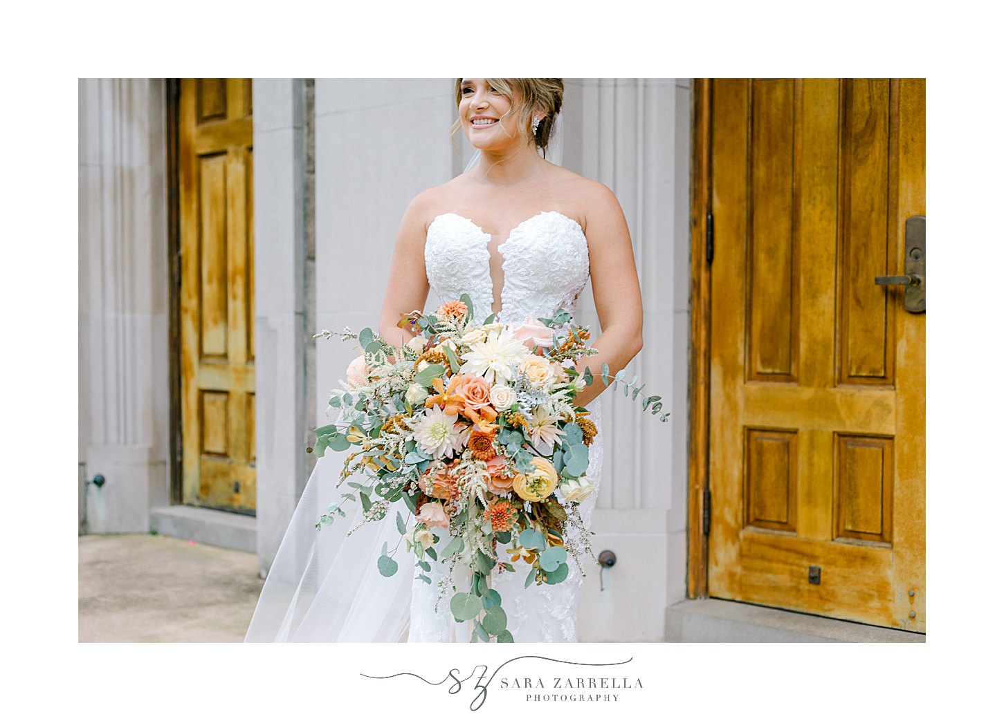 bride holds fall bouquet in front of wooden doors at St Pius Church