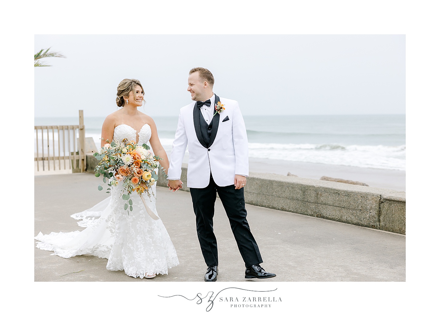 bride and groom walk carrying fall bouquet along beachfront in Westerly RI
