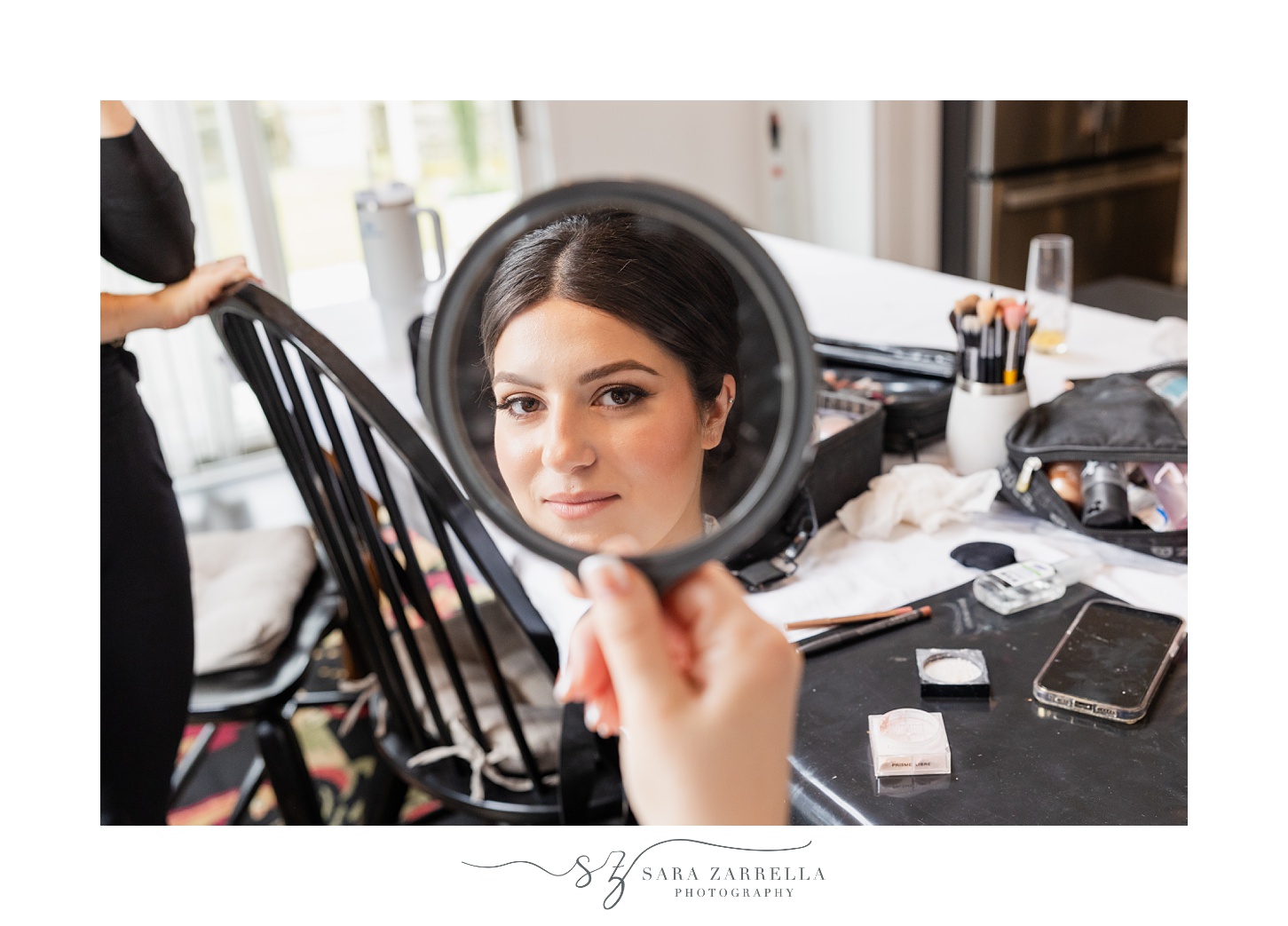 bride looks at reflection in hand mirror while preparing for RI wedding