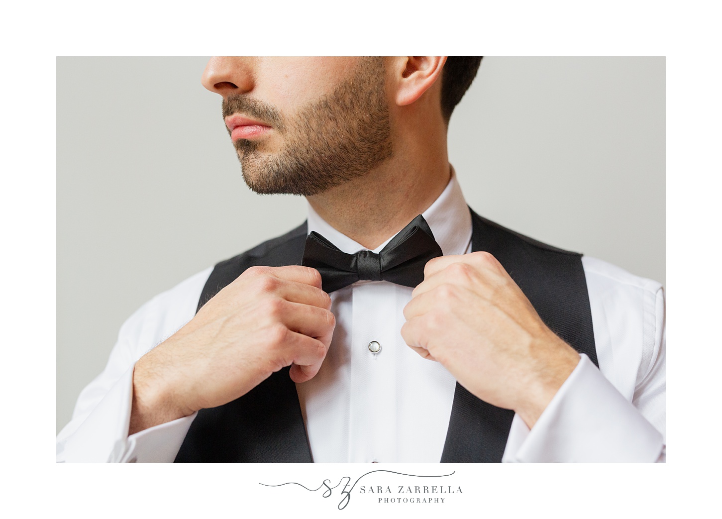 groom adjusts bow tie while preparing for RI wedding 