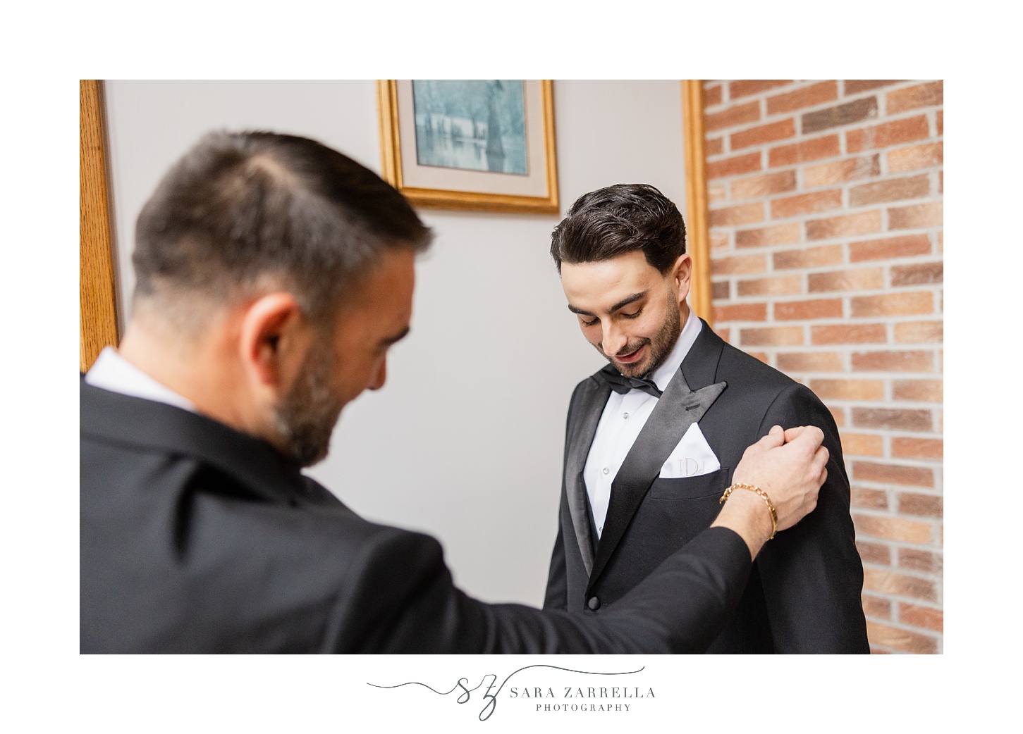 man helps adjust pocket square for groom on wedding morning 