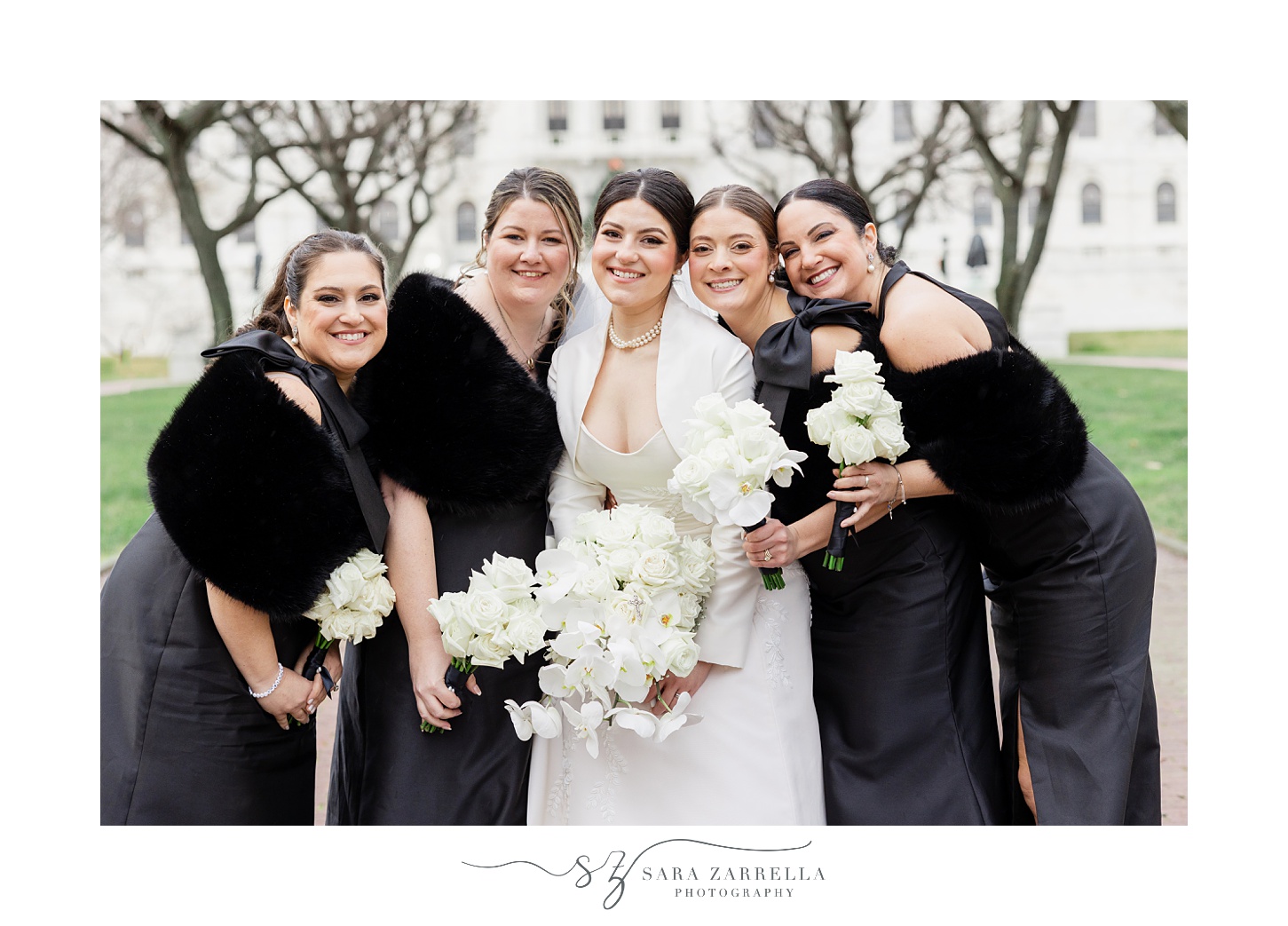 bride hugs close with bridesmaids in black gowns at the RI State House